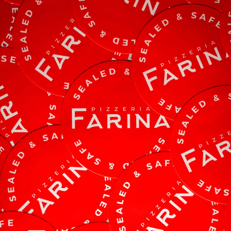 A close-up of many overlapping red circular stickers with "Pizzeria Farina Sealed & Safe" in white text.